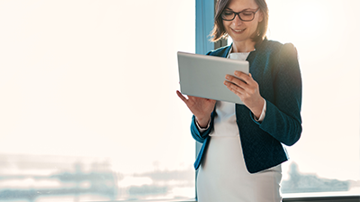 A young businesswoman working on her tablet in front of a window