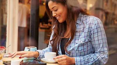 A young woman working on her tablet while enjoying some coffee